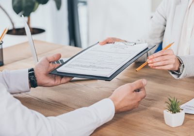 cropped view of businessman and businesswoman holding compensation claim form and pencil at cropped view of businessman and businesswoman holding compensation claim form and pencil at